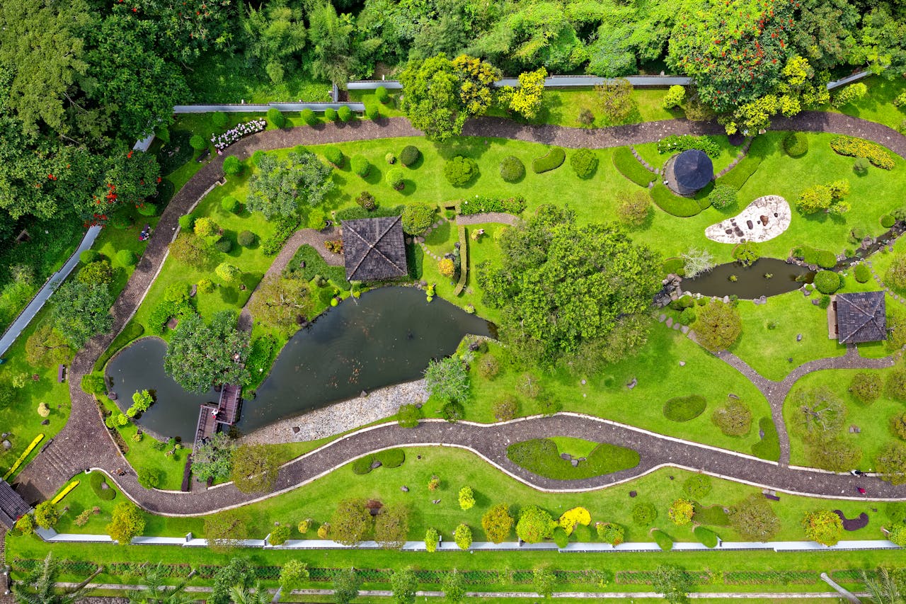 About Stunning aerial shot capturing a lush garden with pathways, ponds, and vibrant greens.
